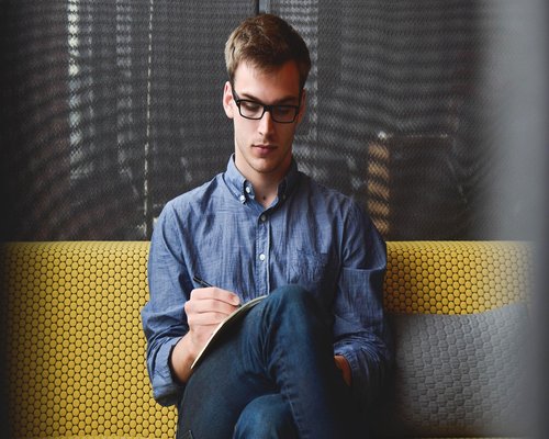Man stretching his neck while sitting in modern office