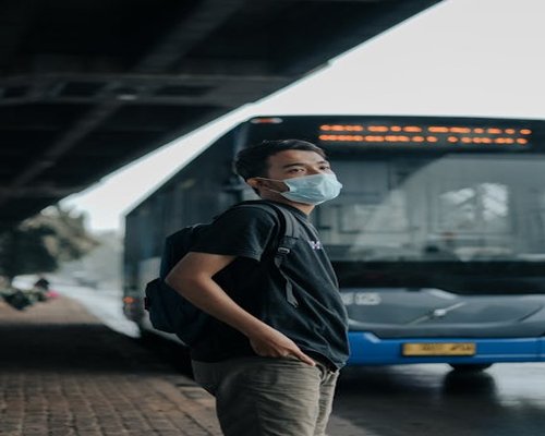 Man walking purposefully near a transjakarta bus stop